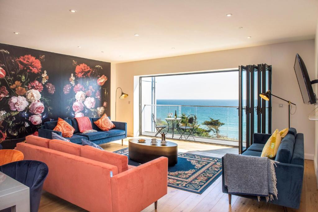 a living room with orange couches and a painting of the ocean at Fulmar in Torpoint