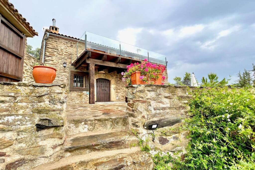 an old stone building with flowers on it at Casa Rural La Cordonera in Herguijuela