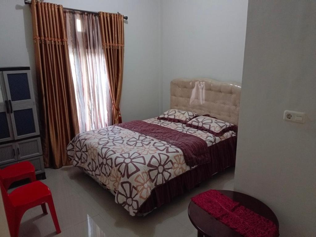 een kleine slaapkamer met een bed en een rode stoel bij Helens Homestay in Enrekang