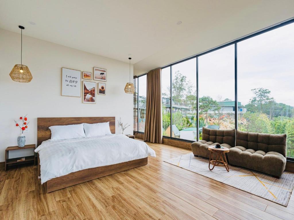 a bedroom with a bed and a couch and windows at Đá Góc Nhà Boutique Hotel in Da Lat