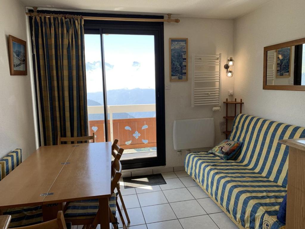 un salon avec un canapé, une table et une fenêtre dans l'établissement Appartement ensoleillé pour 5 pers, balcon sud, proche remontées et commerces, animaux acceptés - FR-1-405-94, à L'Alpe-d'Huez