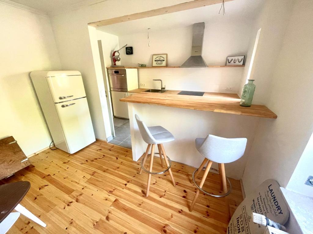 a kitchen with a counter and two white stools at Weener - City Apartment mit Garten in Weener