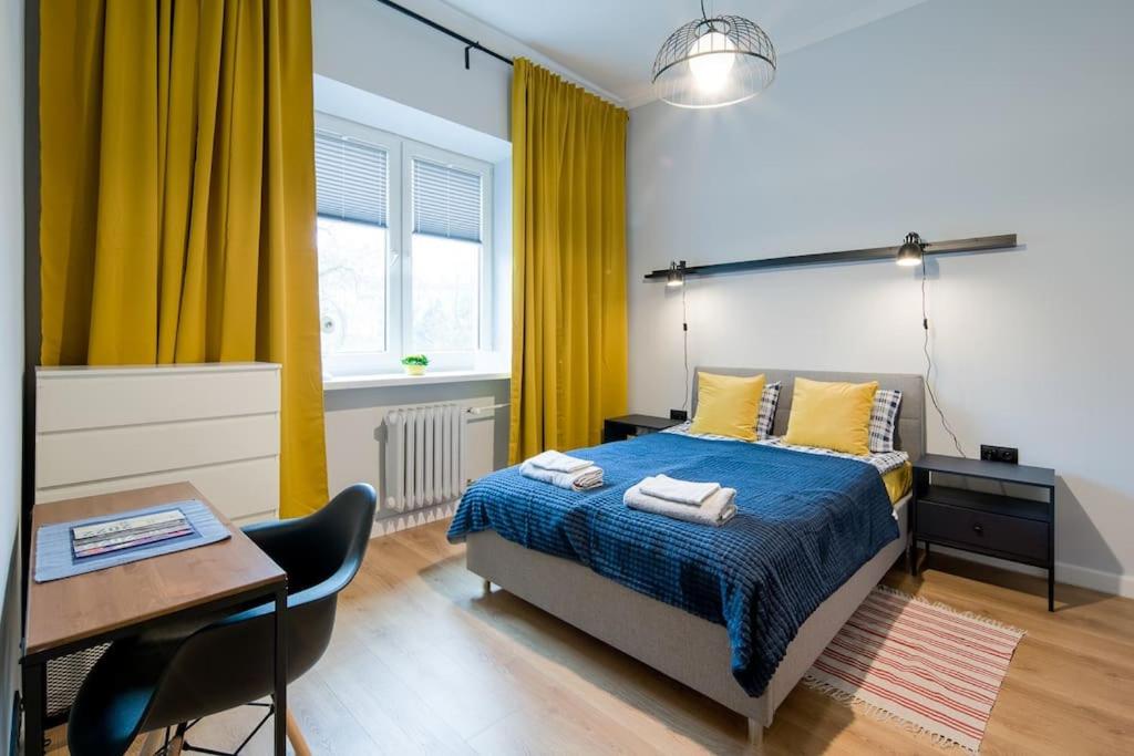 - une chambre avec un lit, une table et des rideaux jaunes dans l'établissement Nowa Huta Super Star, à Cracovie