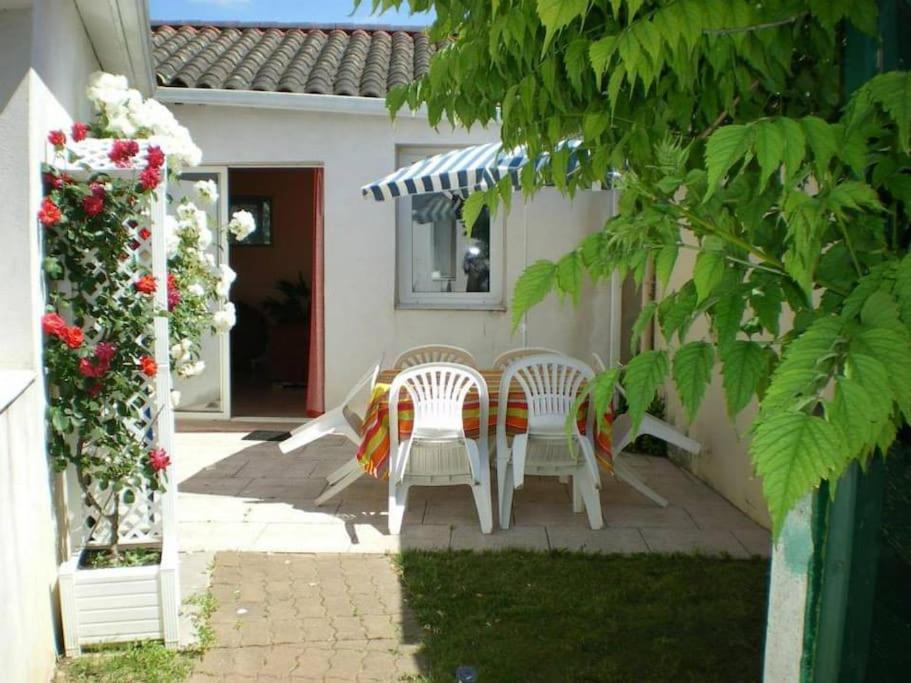 un patio con 2 sillas y una mesa frente a una casa en Maison centre Jard et à 8min à pied de la plage, en Jard-sur-Mer