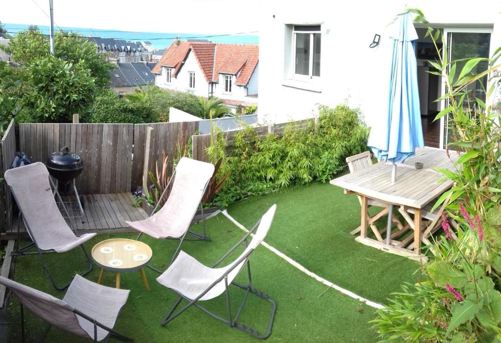 un patio avec des chaises, une table et un parasol dans l'établissement Mer en Vue - 2 Chambres- 4 Personnes, à Fécamp