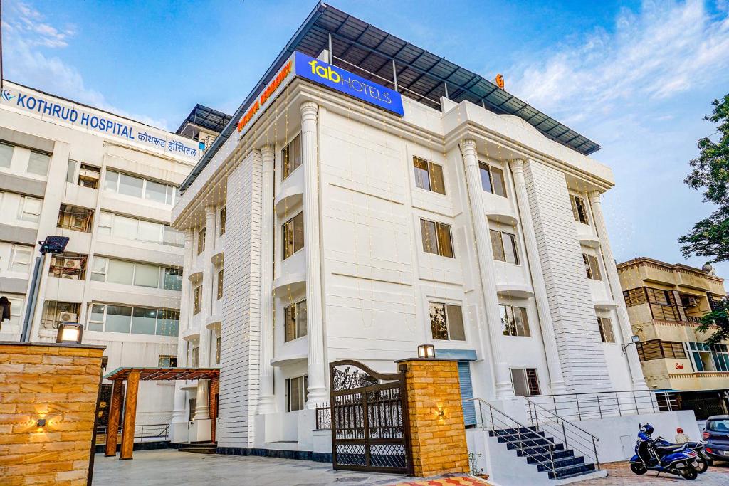 un edificio blanco con una señal azul en FabHotel Prime Shourya Residency, en Pune