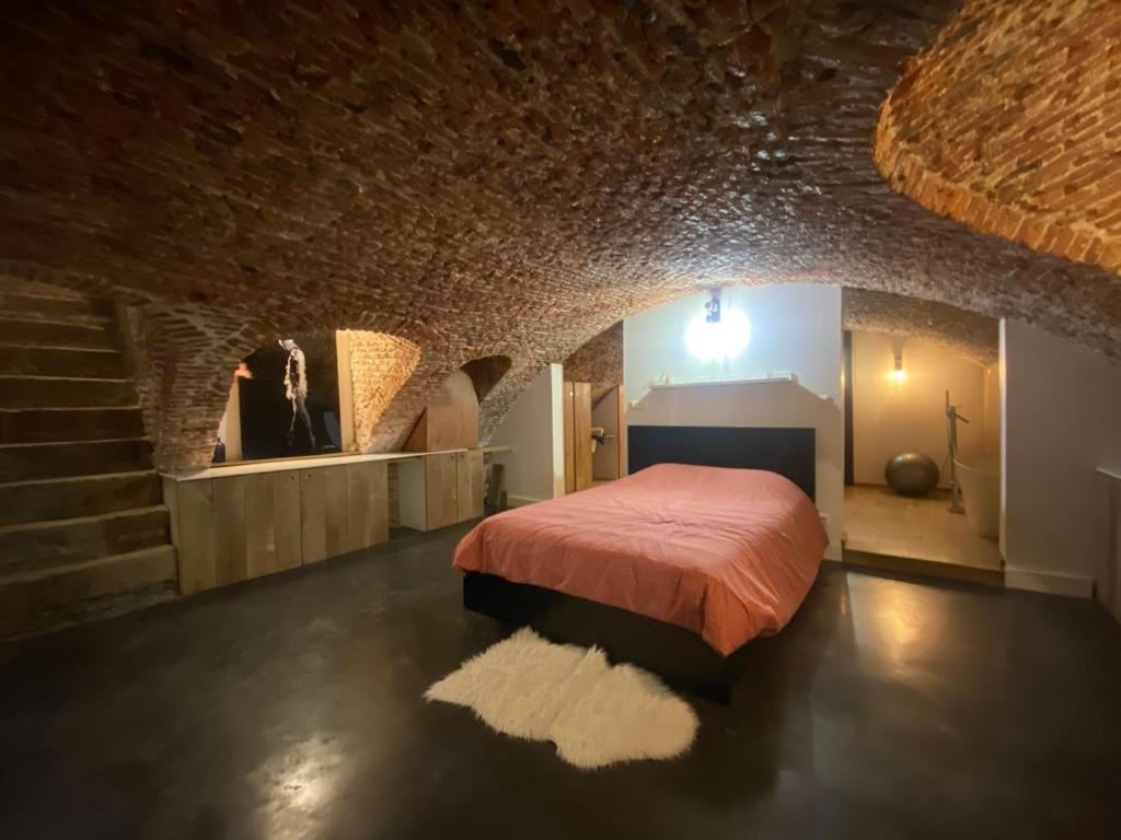um quarto com uma cama numa parede de tijolos em Au Beau Lieu de Metz em Lille