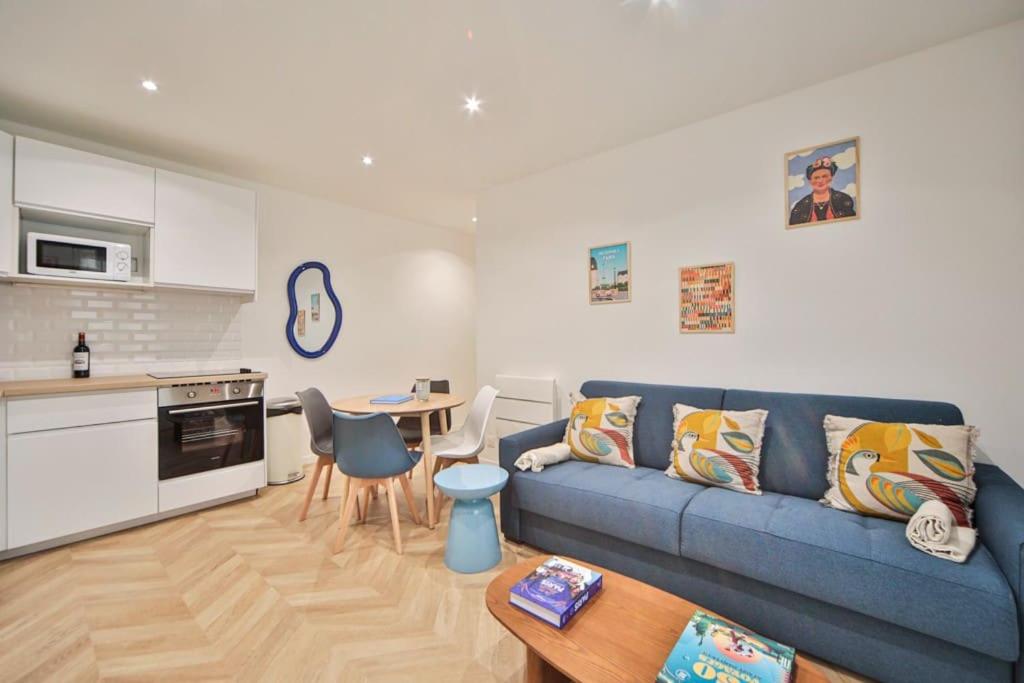 un salon avec un canapé bleu et une table dans l'établissement Appartement de charme proche du Canal Saint-Martin, à Paris