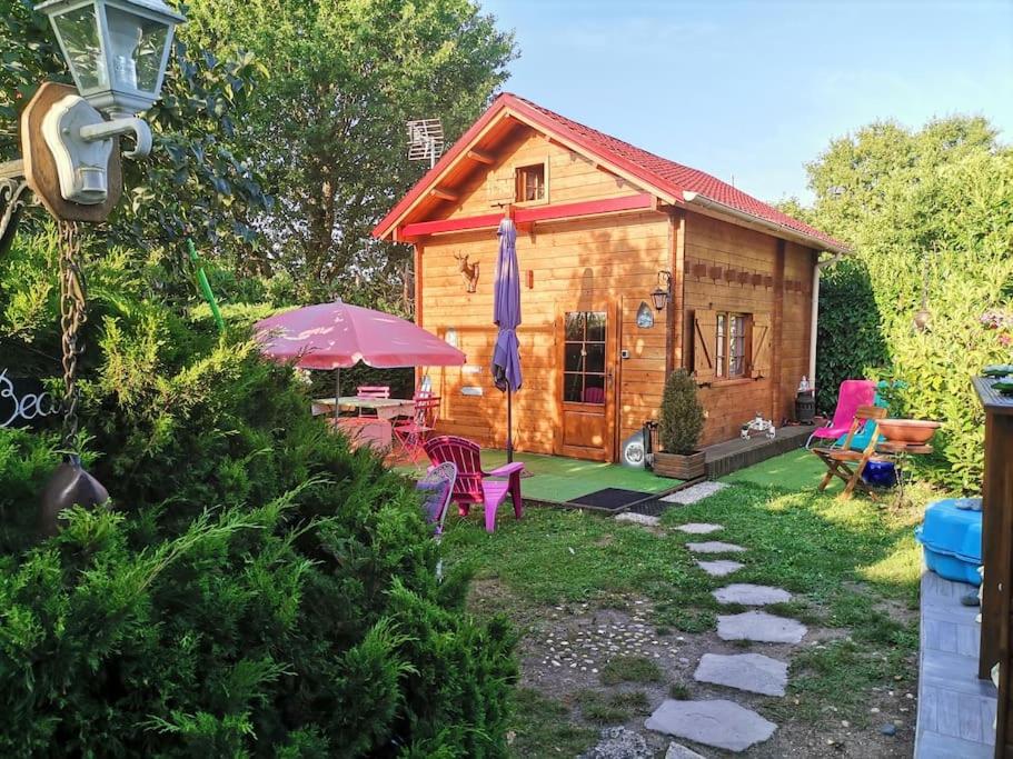 a log cabin with a table and chairs and an umbrella at petite location insolite d un chalet in Saran