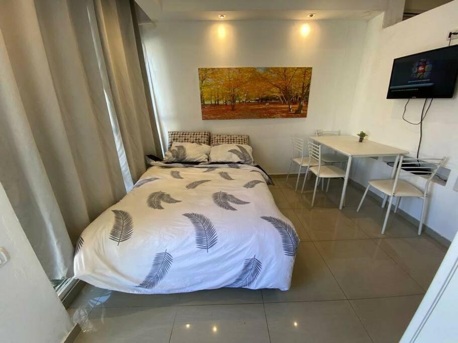 Sunny Garden. YBG. 1 Bedroom Apt. Quiet في تل أبيب: غرفة نوم بسرير وطاولة مع كراسي