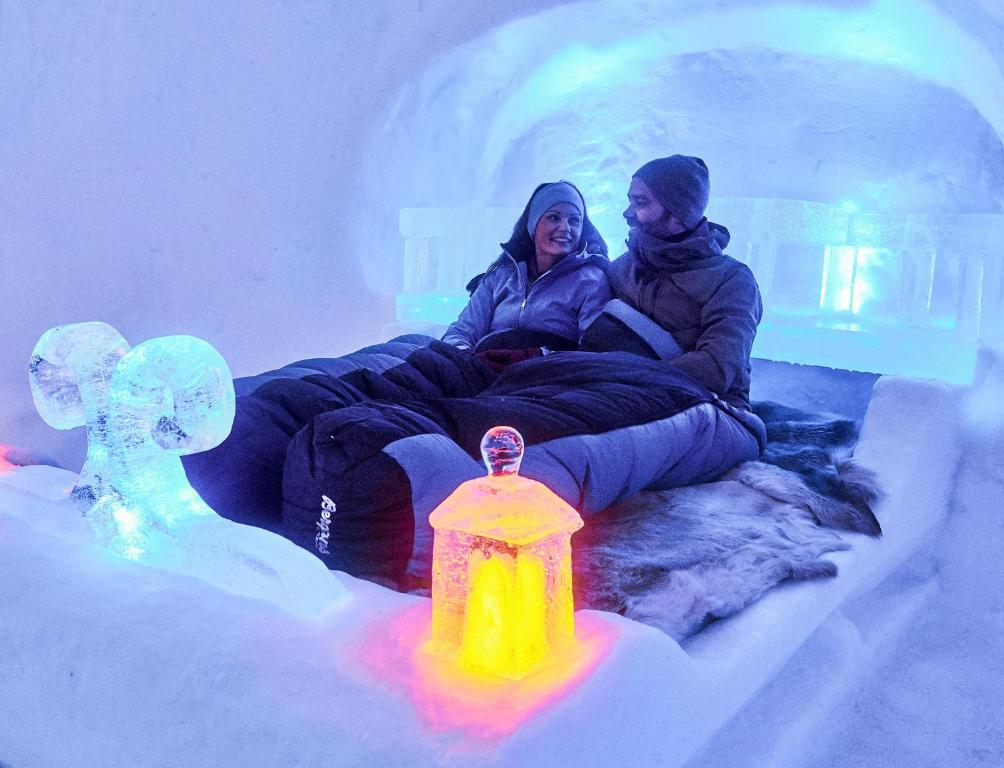 dwoje ludzi siedzących w lodowym igloo z hydrantem pożarowym w obiekcie Hunderfossen Snow Hotel w mieście Hafjell