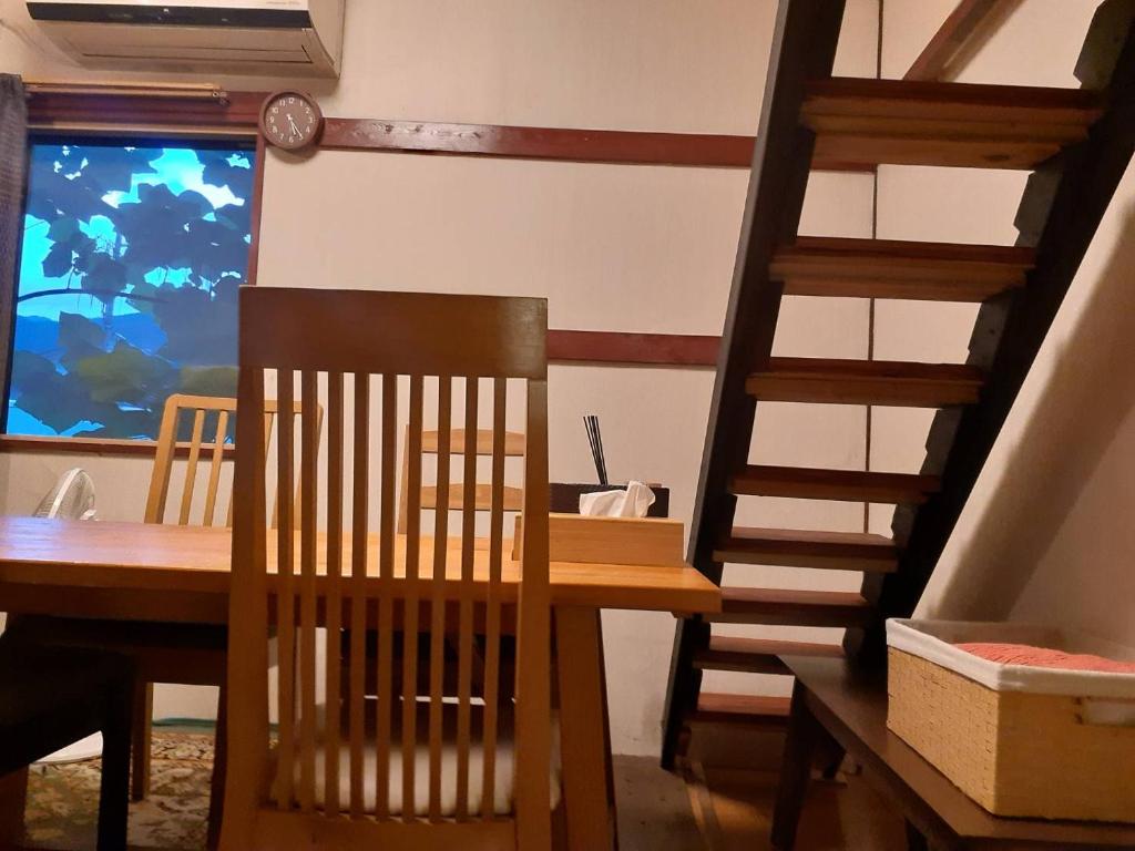 une salle à manger avec une table en bois et un escalier dans l'établissement HAKUBA IKEDA LIFE KAN APARTMENTS, à Hakuba