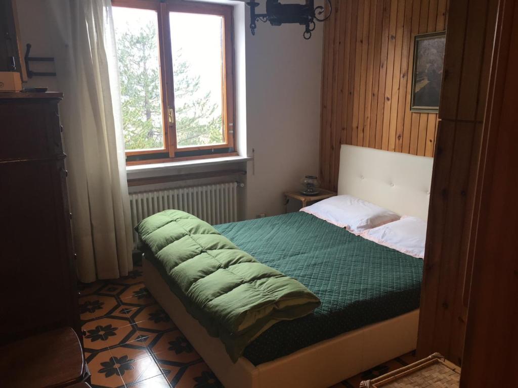 a bedroom with a bed with a green comforter and a window at Zeta House in Rivisondoli