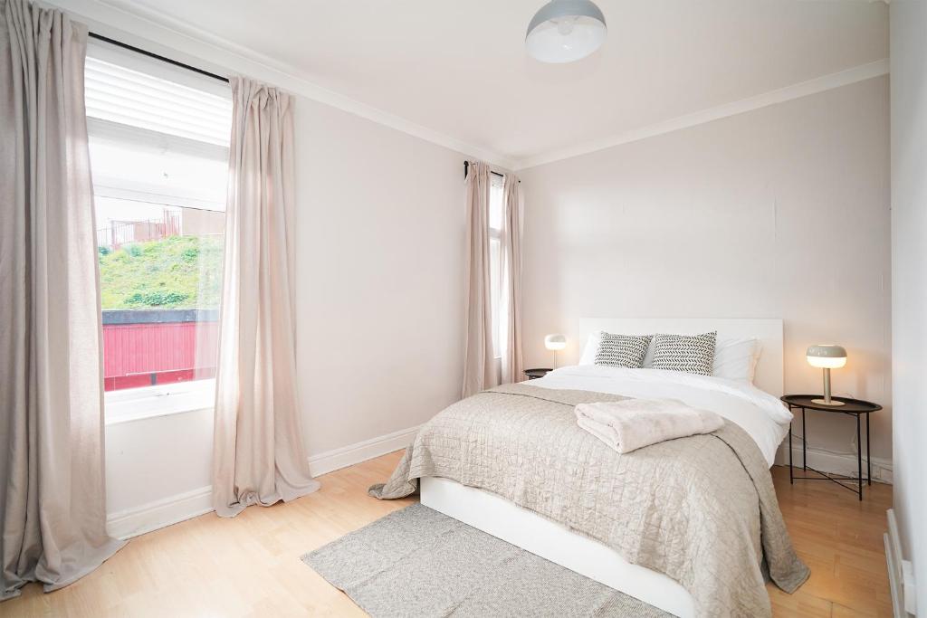 a white bedroom with a bed and a window at Stadium View, entire private house, close to city centre, free WiFi in Sheffield