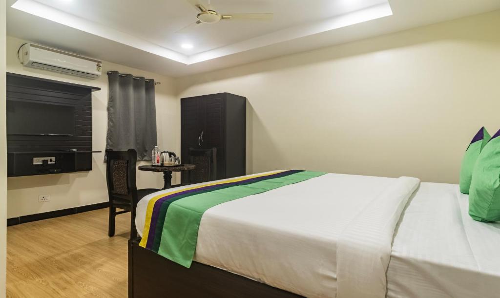 a bedroom with a bed and a table with a chair at Treebo Trend Address Inn Jubilee Hills in Hyderabad