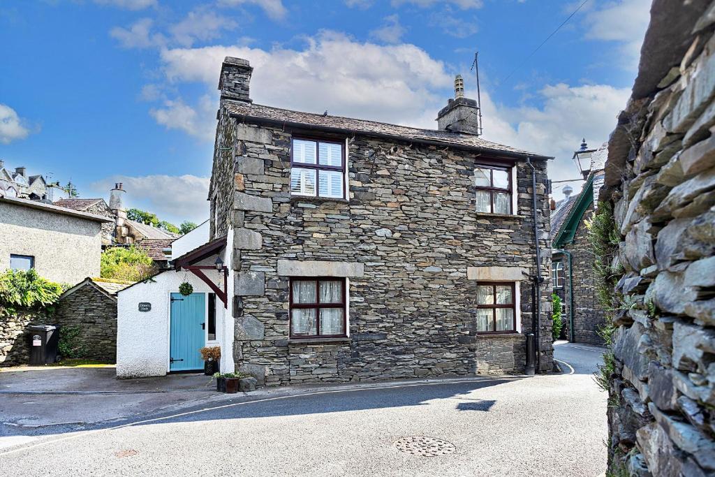 an old stone house with a blue door on a street at Finest Retreats - Otters Holt in Ambleside