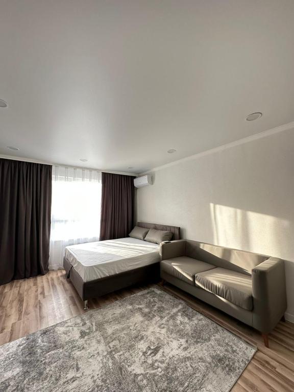 um quarto com uma cama, um sofá e um tapete em Отличная квартира в центре города Шымкент. ЖК Тумар апартамент em Shymkent
