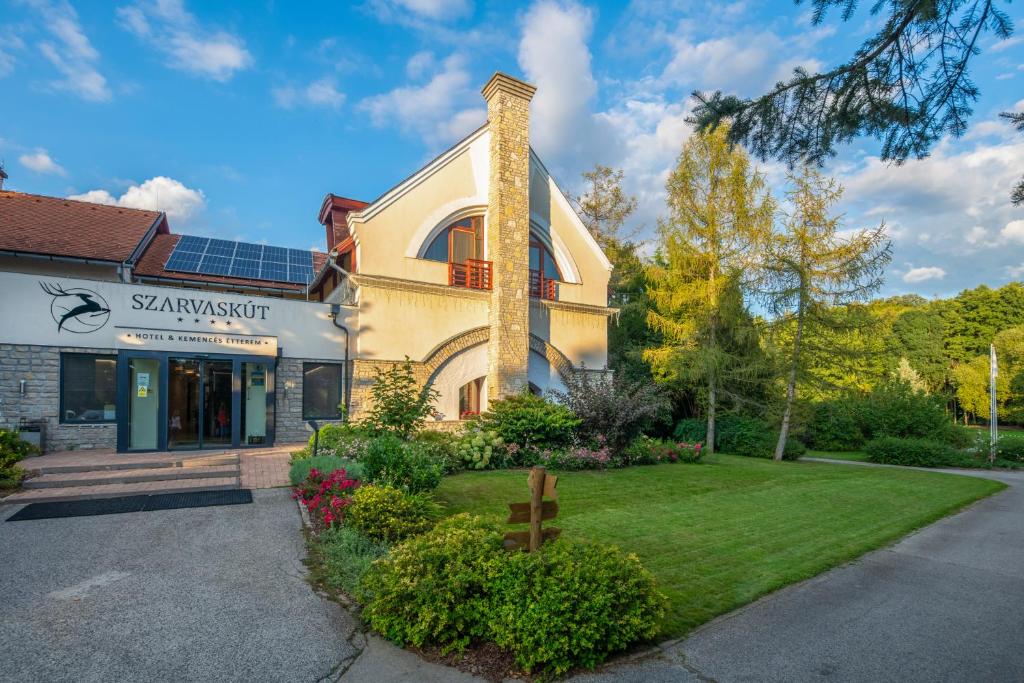 a house with a cross in front of a building at Szarvaskút Hotel in Zirc