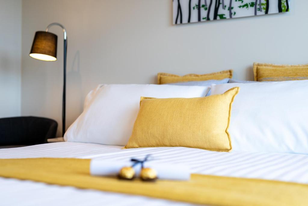 1 cama blanca con almohada amarilla y tijeras en Oceana B&B, en Howrah