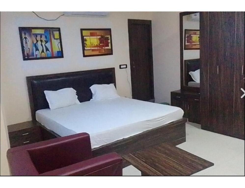 a bedroom with a white bed and a chair at Hotel Saraswati International, Muzaffarapur in Muzaffarpur