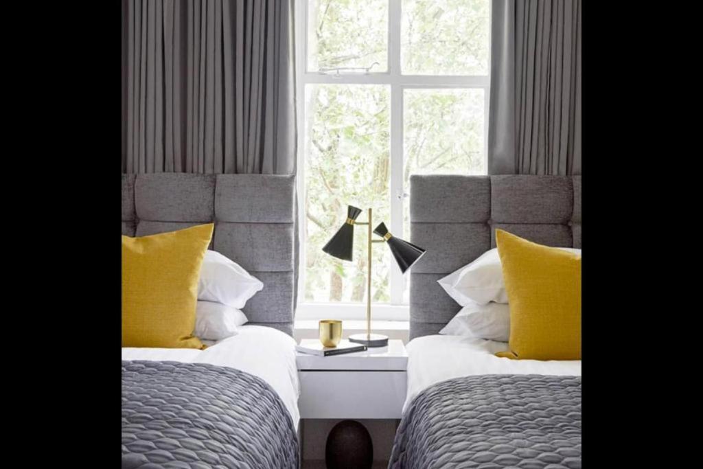 a bedroom with two beds with yellow pillows and a window at Lovely 2-Bed Apartment in Stanford-le-Hope in Stanford-le-Hope