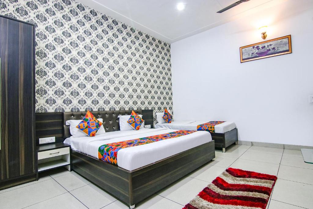1 dormitorio con 2 camas y pared estampada en FabHotel Ace, en Ludhiana
