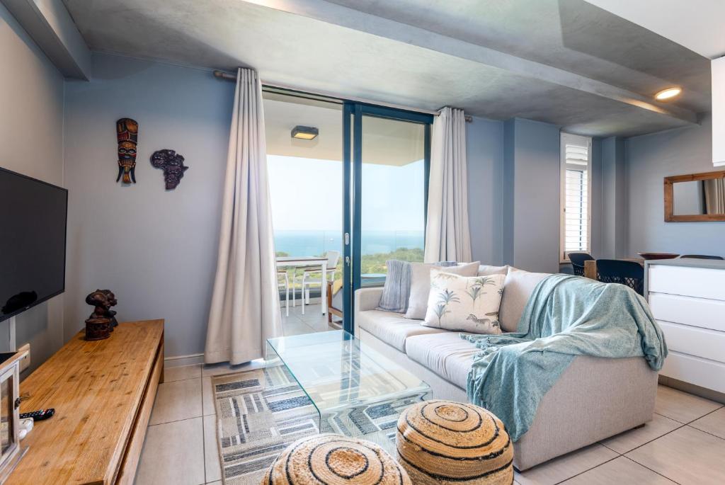 a living room with a couch and a glass table at Gorgeous Coral Point Sibaya in Umdloti