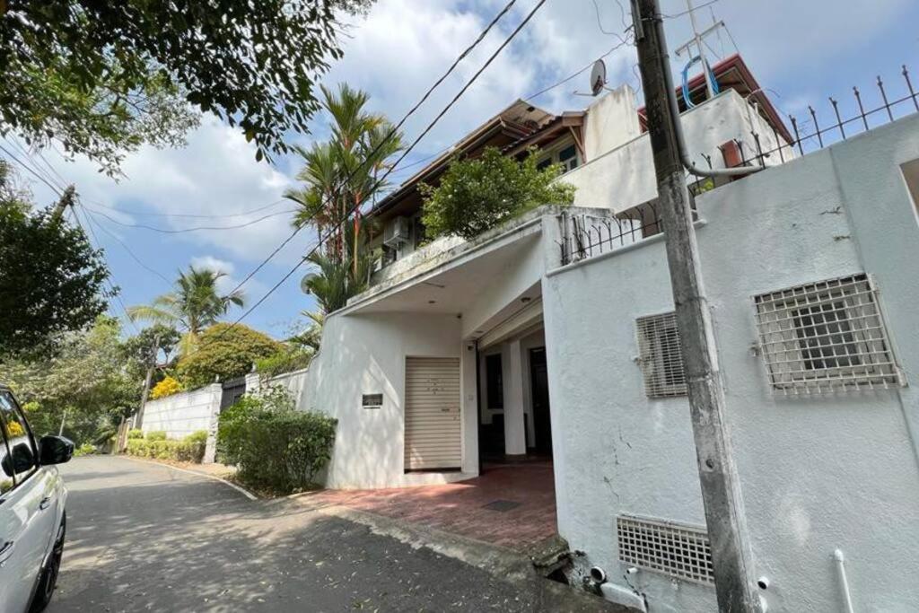 um edifício branco com um portão ao lado em Luxury Fully furnished house for 8 people ! em Sri Jayewardenepur- Kotte