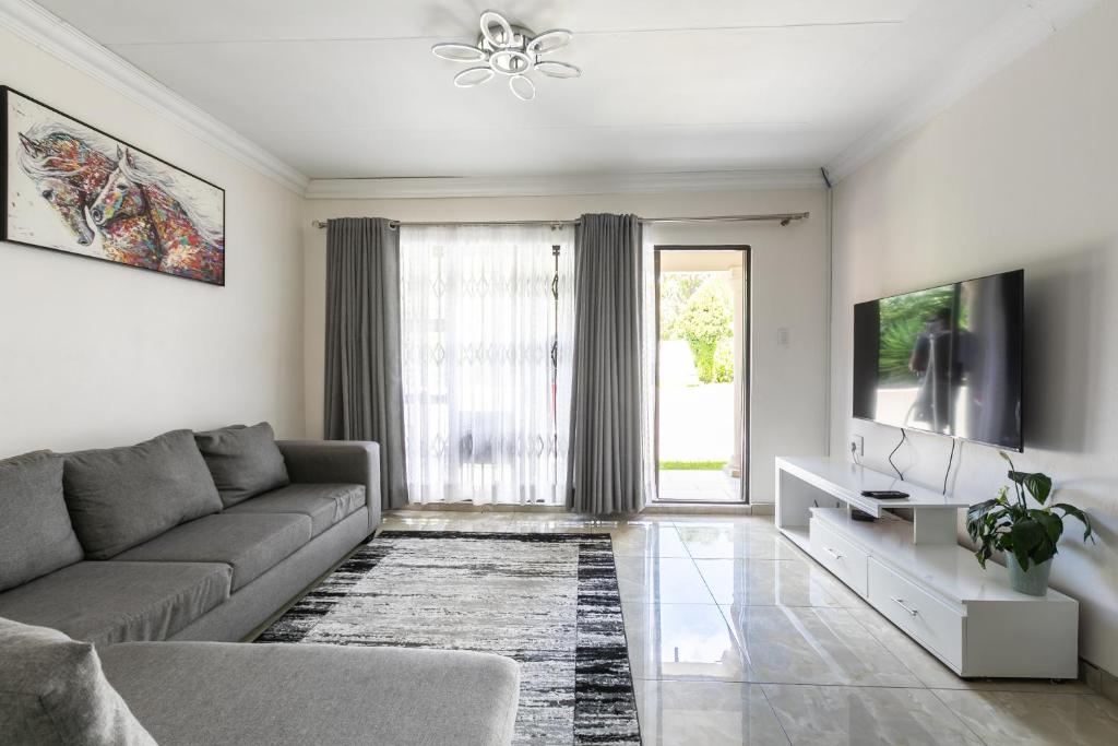 een woonkamer met een bank en een tv bij Signature Lodge in Kempton Park