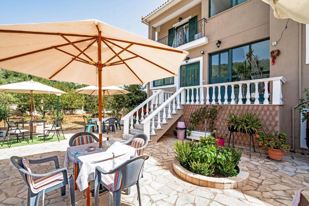 patio ze stołami, krzesłami i parasolem w obiekcie Daratos apartment 3 w mieście Kefalonia