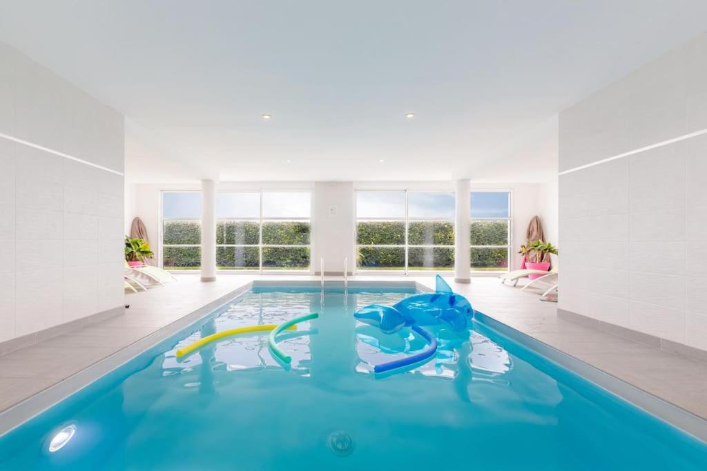 uma piscina com escorrega numa casa em Villa Enora Bretagne Piscine Intérieure Partagée Jacuzzi privatif 100m Plage em Sibiril