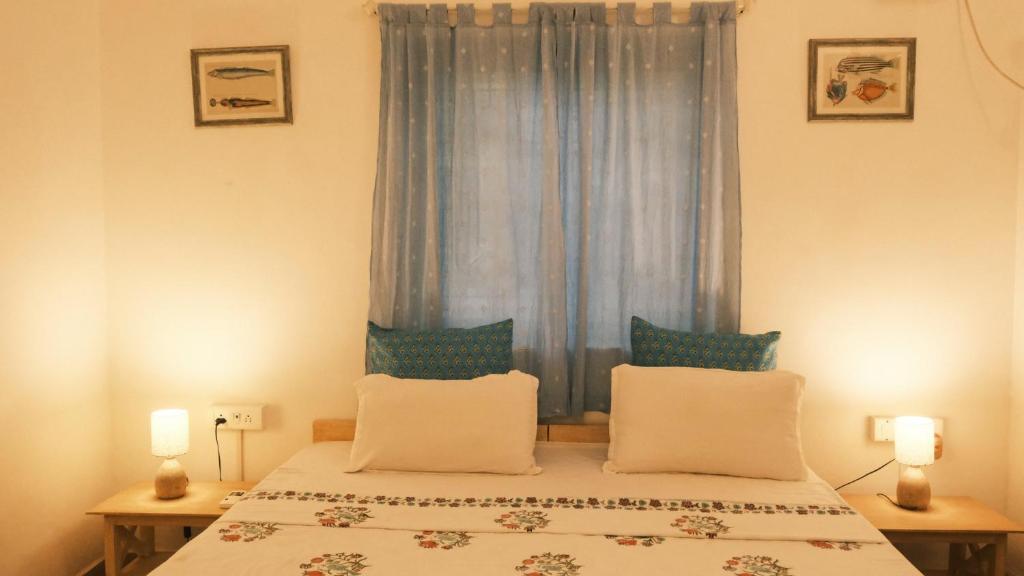 um quarto com uma cama e uma janela com cortinas azuis em Coco Moon em Morjim