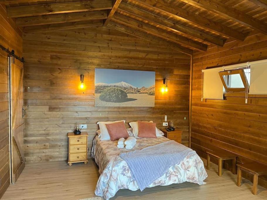 1 dormitorio con 1 cama en una pared de madera en Fabulosa Cabaña vía a El Teide en La Orotava