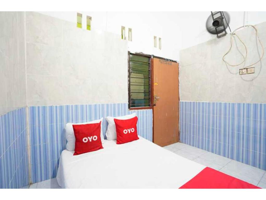 1 dormitorio con 1 cama con 2 almohadas rojas en OYO Life 93061 Kost Vicky Syariah en Surabaya