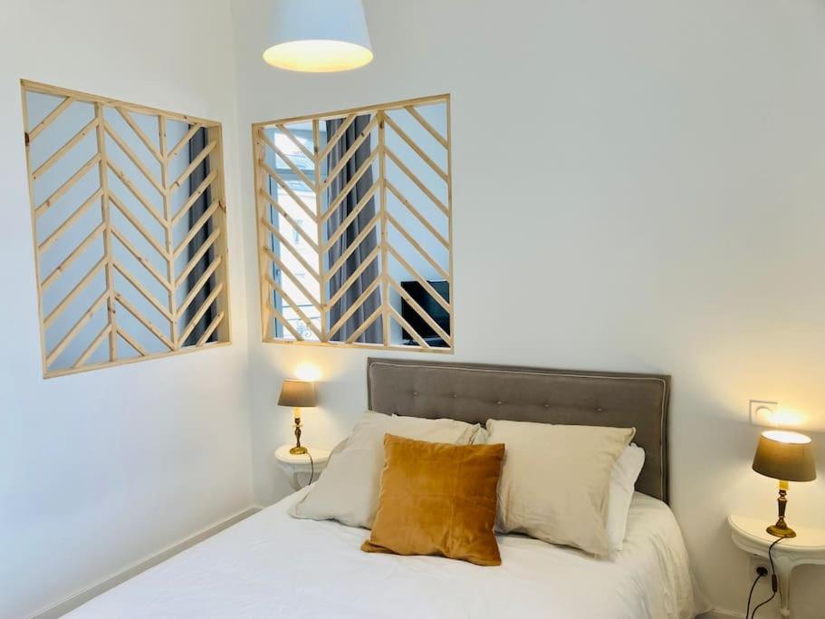 a bedroom with a white bed with two windows at La Belle Consigne - Appartements Dinan Centre Gare in Dinan