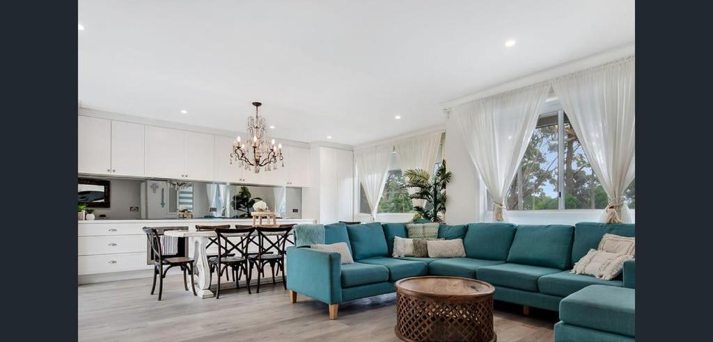 uma sala de estar com um sofá azul e uma cozinha em Boho Beach House em Vincentia
