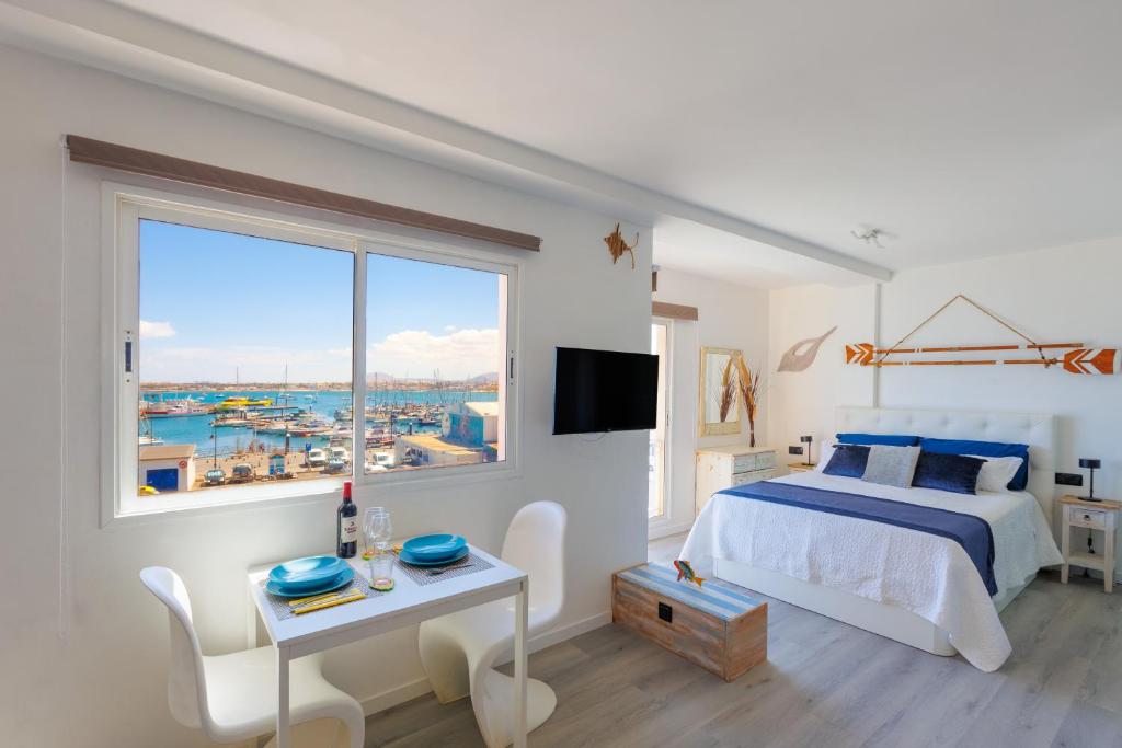 une chambre blanche avec un lit et une grande fenêtre dans l'établissement EL VELERO, à Corralejo