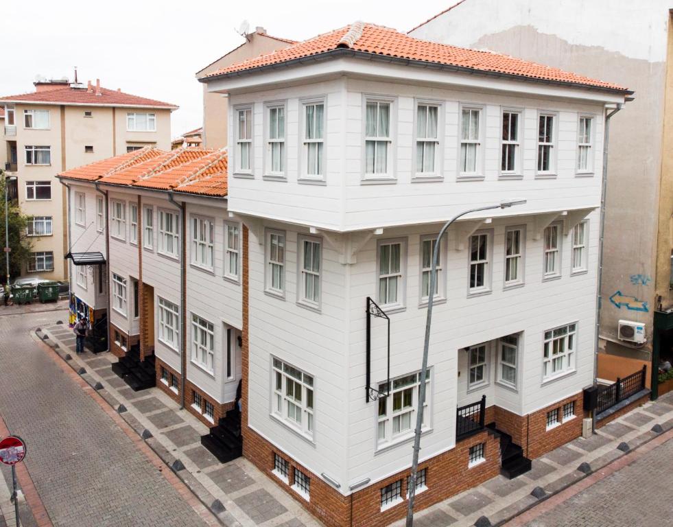 un bâtiment blanc avec un toit rouge dans une rue dans l'établissement Best Pasaport Pier Otel Kadıköy, à Istanbul