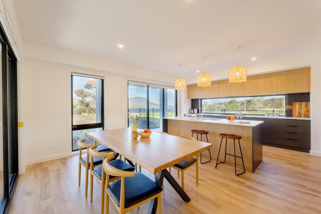 cocina y comedor con mesa de madera y sillas en Hobart 4-bedroom Spacious Waterfront House en Hobart