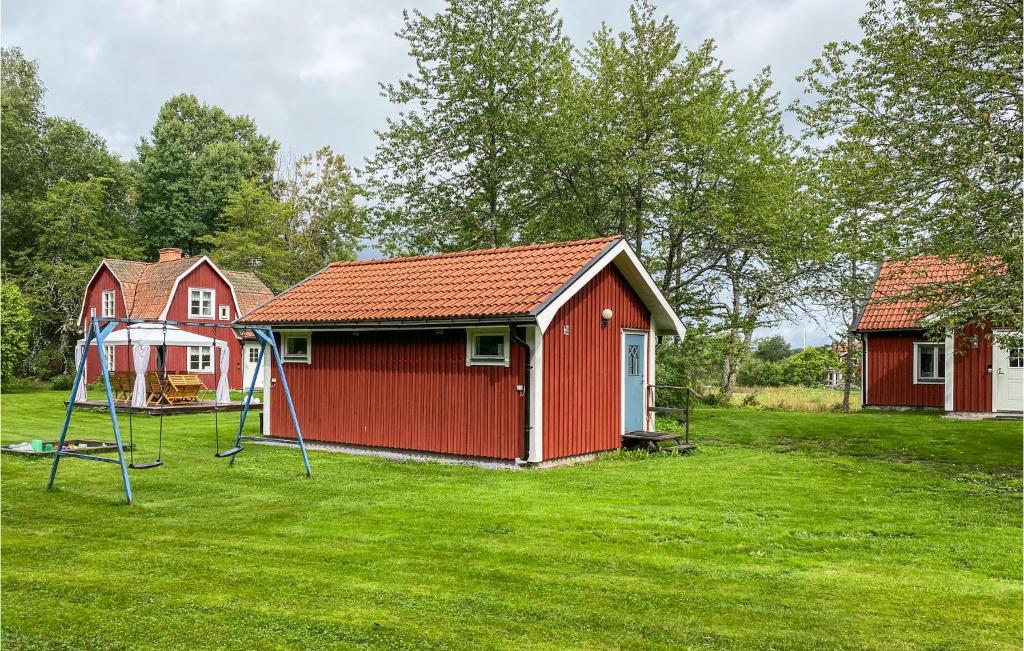une maison rouge avec une balançoire dans une cour dans l'établissement Cozy Home In Edsbruk With Ethernet Internet, à Edsbruk