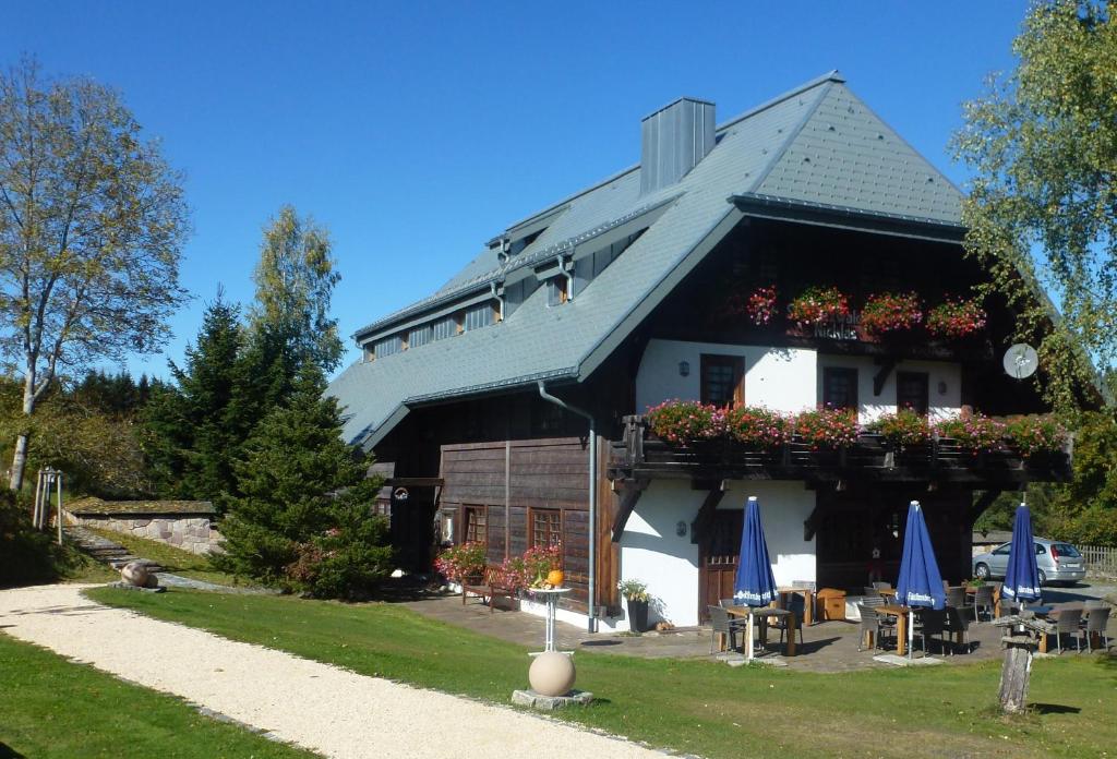 a building with a balcony with tables and umbrellas at Schwarzwaldhof Nicklas in Bonndorf im Schwarzwald