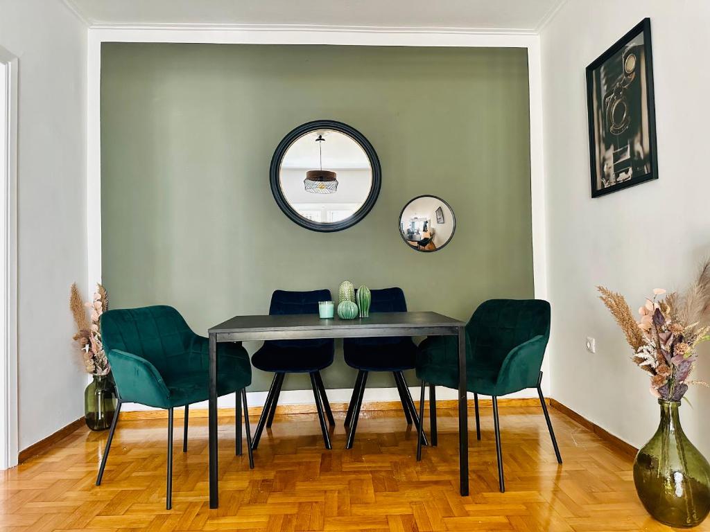 een eettafel met groene stoelen en een spiegel bij Chez Ethan, 5 min à pied de l'Acropole in Athene