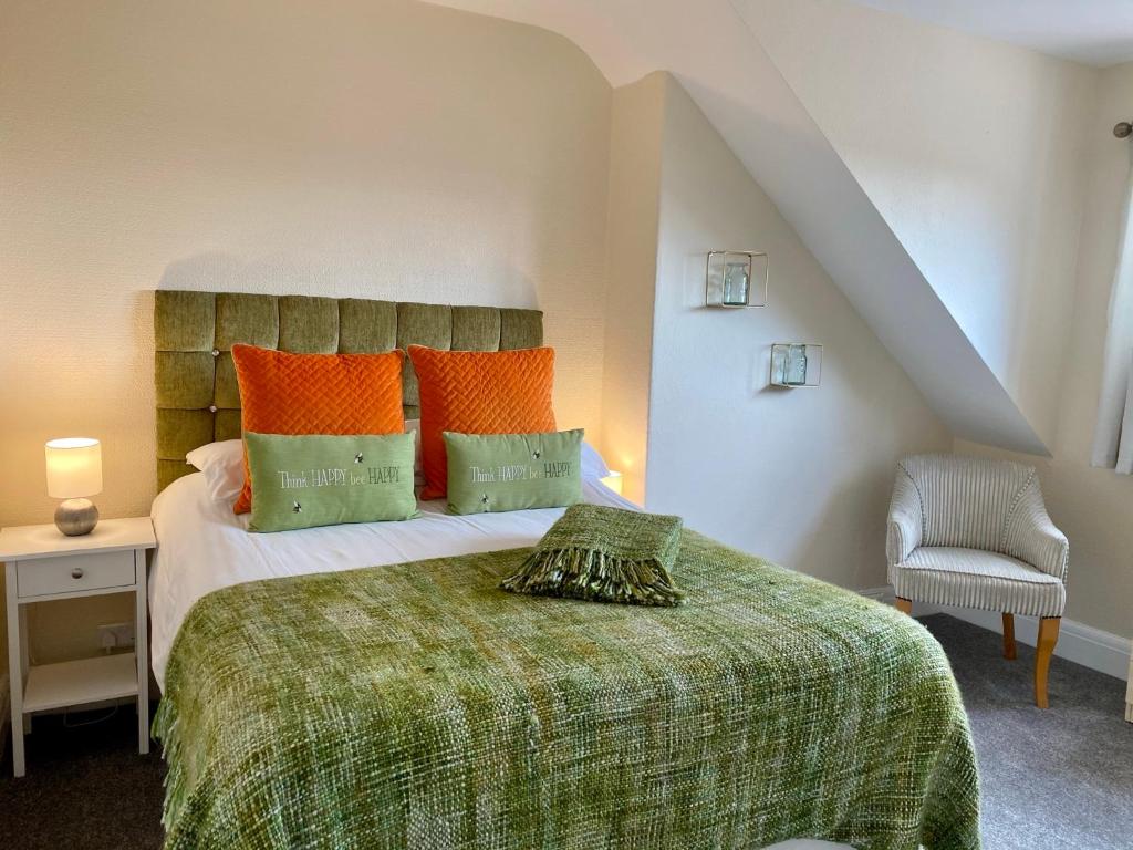 スランディドノにあるCwtch Guesthouseのベッドルーム1室(オレンジと緑の枕が付いたベッド1台付)