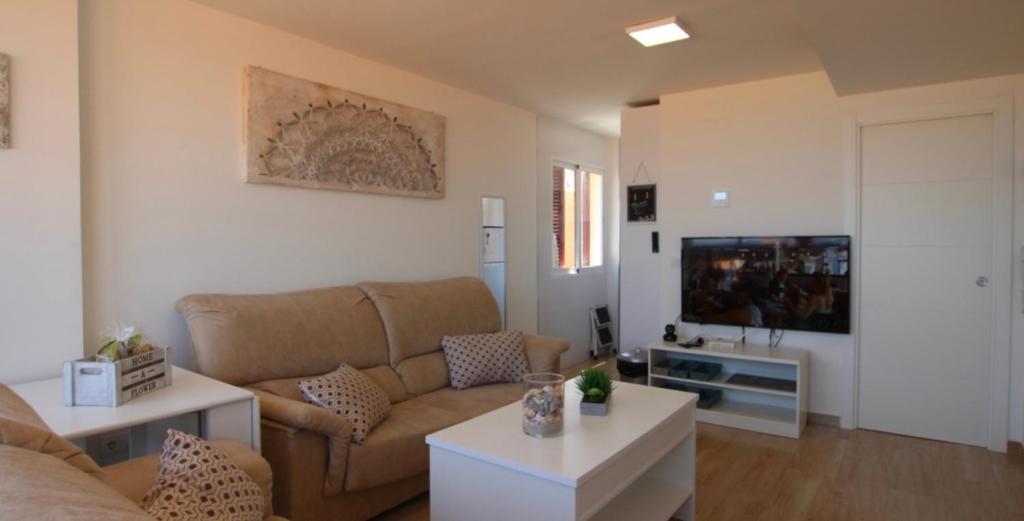 sala de estar con sofá y TV en Apartamento jardin del mar 7.5, en La Manga del Mar Menor