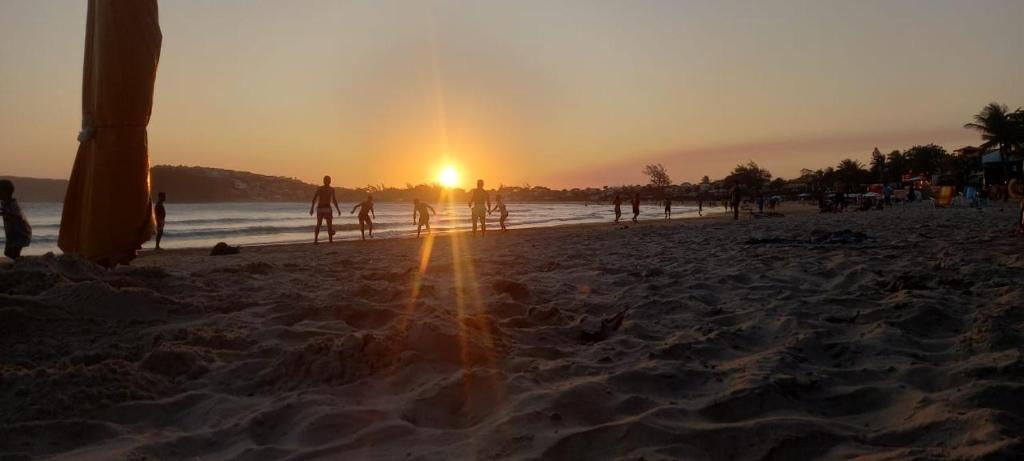 un grupo de personas caminando por la playa al atardecer en Recanto Da Ursa, en Búzios