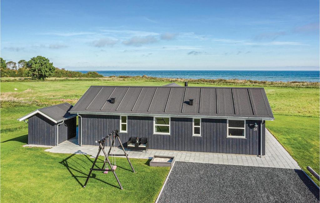 a black house with a playground next to the ocean at Three-Bedroom Holiday Home In Nordborg in Nordborg