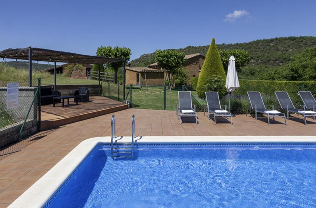 una piscina con sillas, una mesa y una sombrilla en Cal Colom en Puigreig