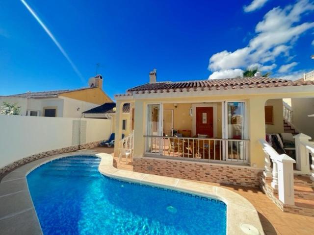 a house with a swimming pool in front of a house at Villa Limon Playa Flamenca in Alicante