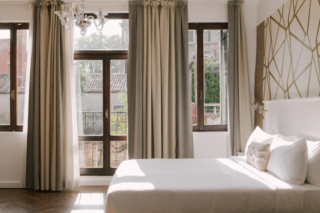 a bedroom with a white bed and windows at Salute Palace powered by Sonder in Venice