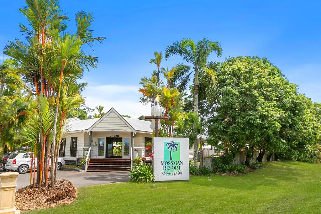un cartel frente a una casa con palmeras en Mossman Resort Holiday Villas, en Mossman